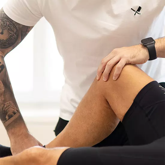 Ein Physiotherapeut behandelt einen Patienten am Knie.