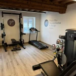 Physio Plus Geräteraum mit Schriftzug an der Wand und diversen Geräten zum Trainieren 