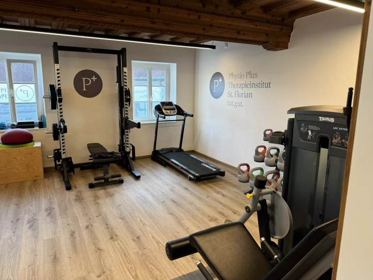 Physio Plus Geräteraum mit Schriftzug an der Wand und diversen Geräten zum Trainieren 